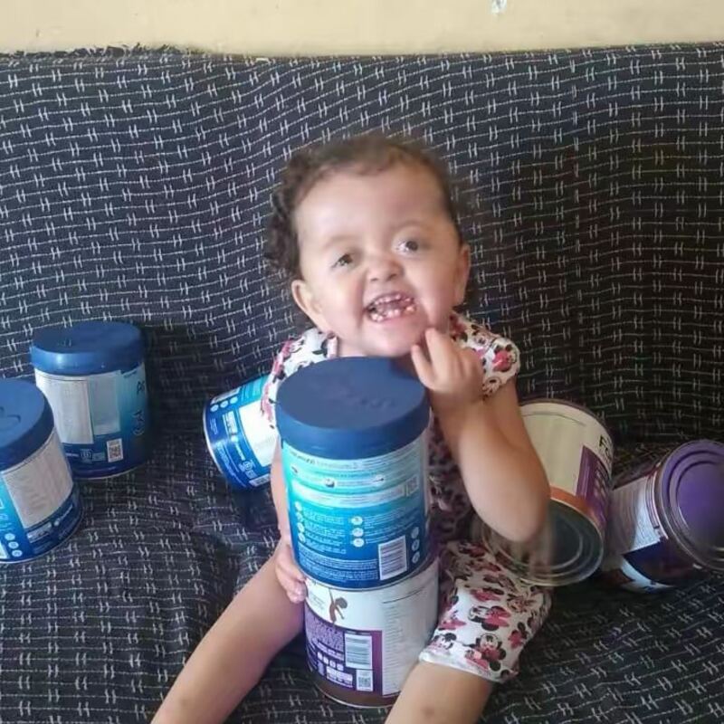 Criança sorrindo ao lado de doações recebidas do ICCA